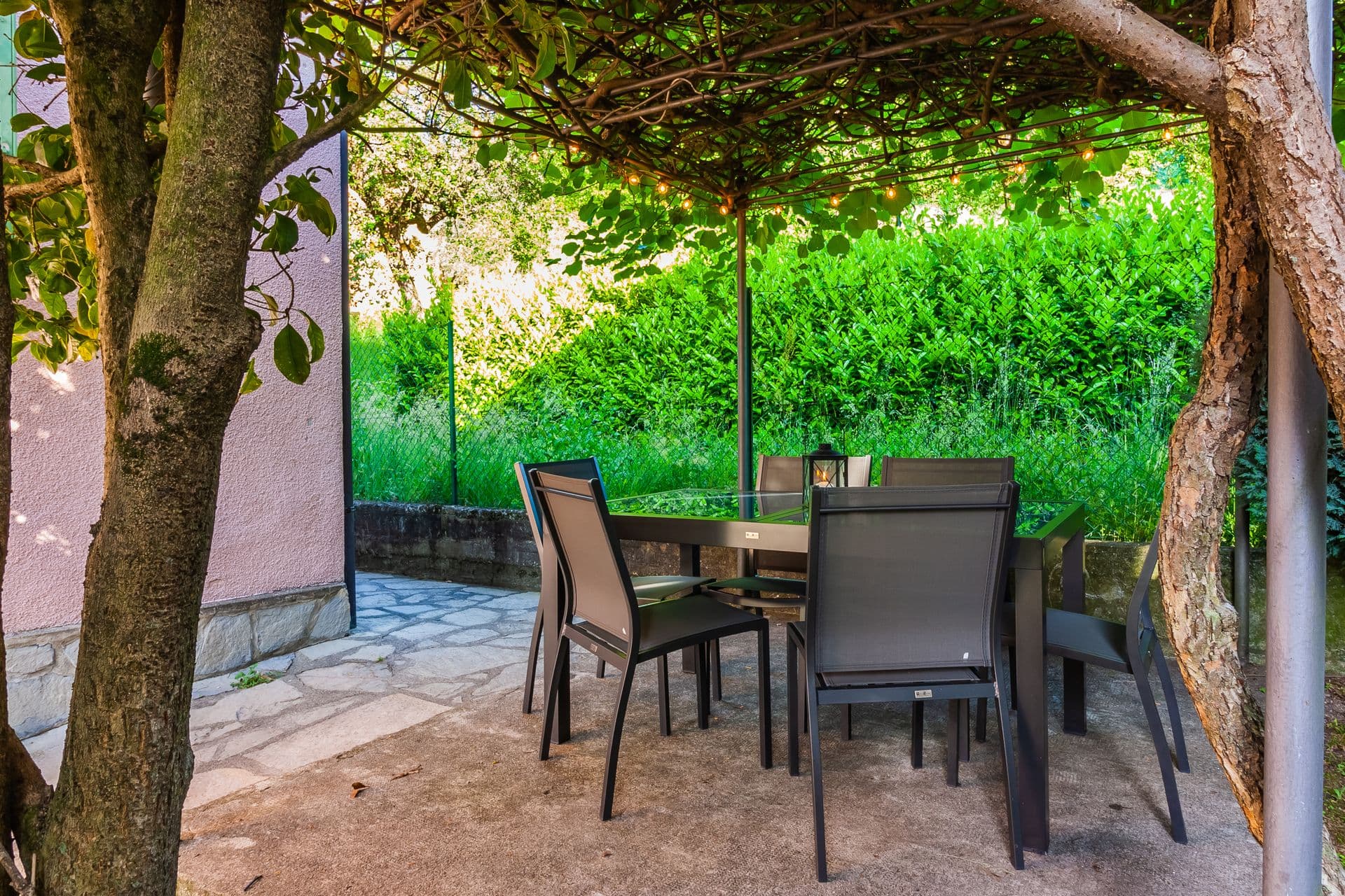 Shaded garden dining area under a vine-covered pergola at So Bellagio