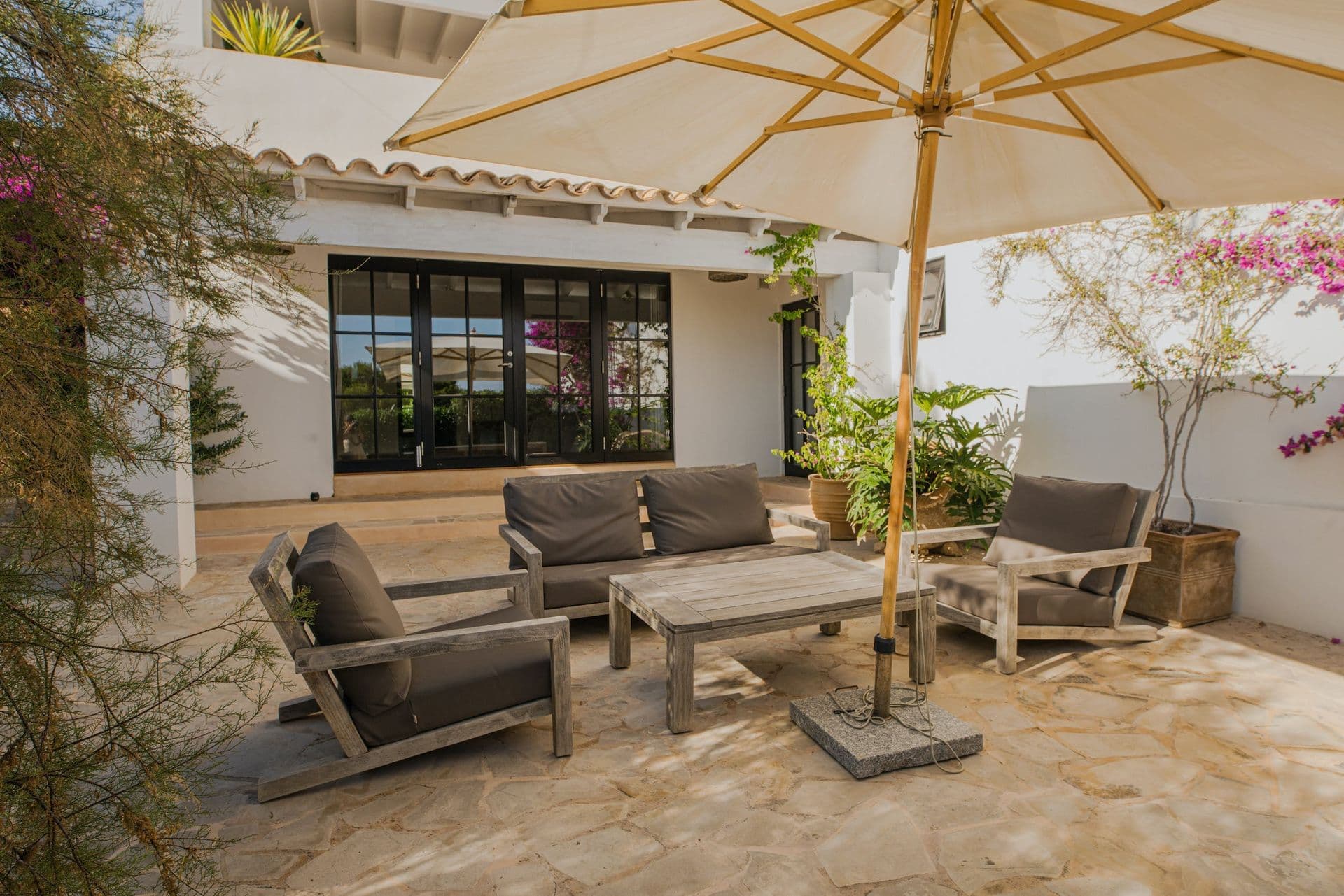 Rattan lounge seating beneath a parasol against the whitewashed villa facade at New Beat