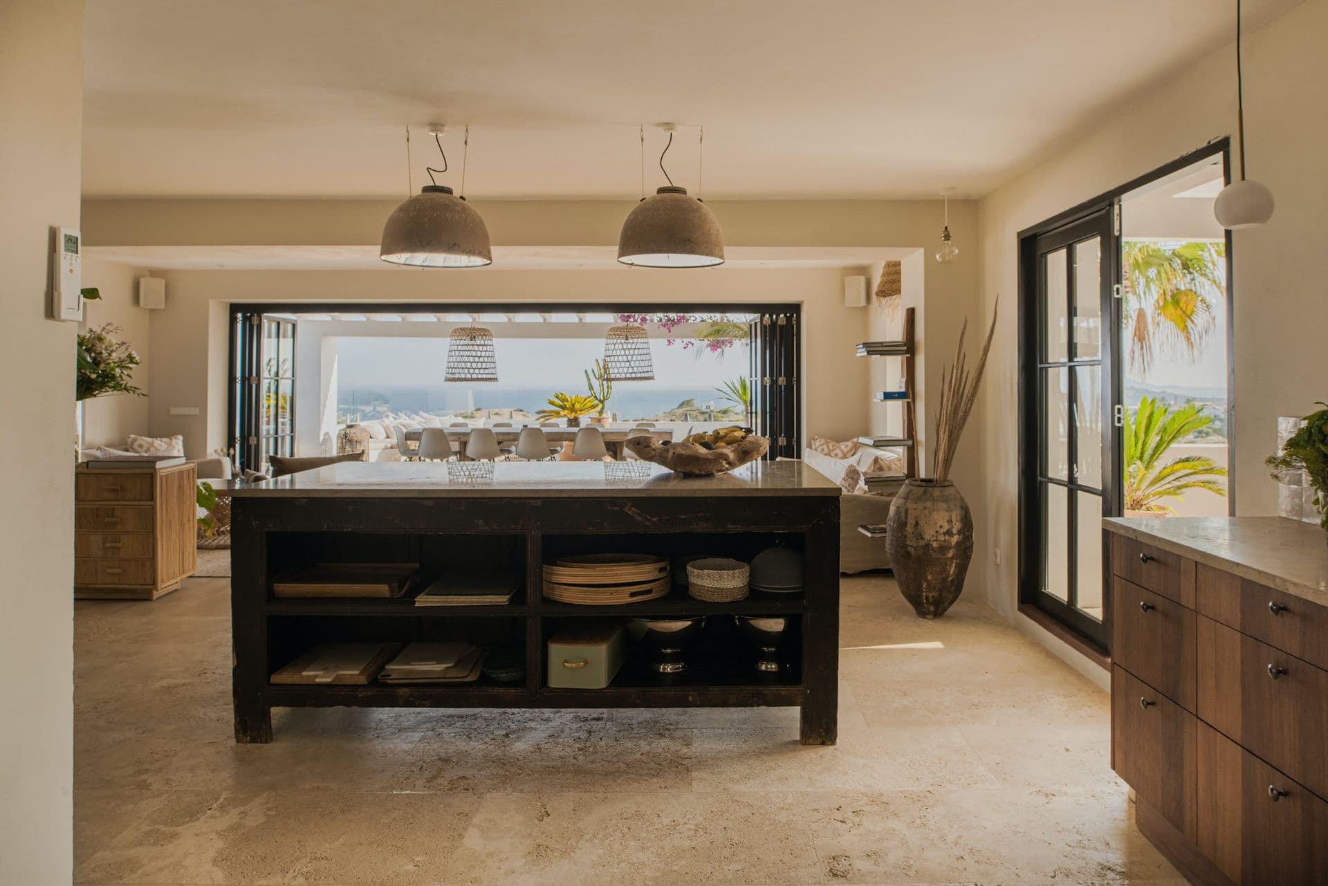 Dark wood kitchen island beneath pendant lighting in an open plan interior at New Beat