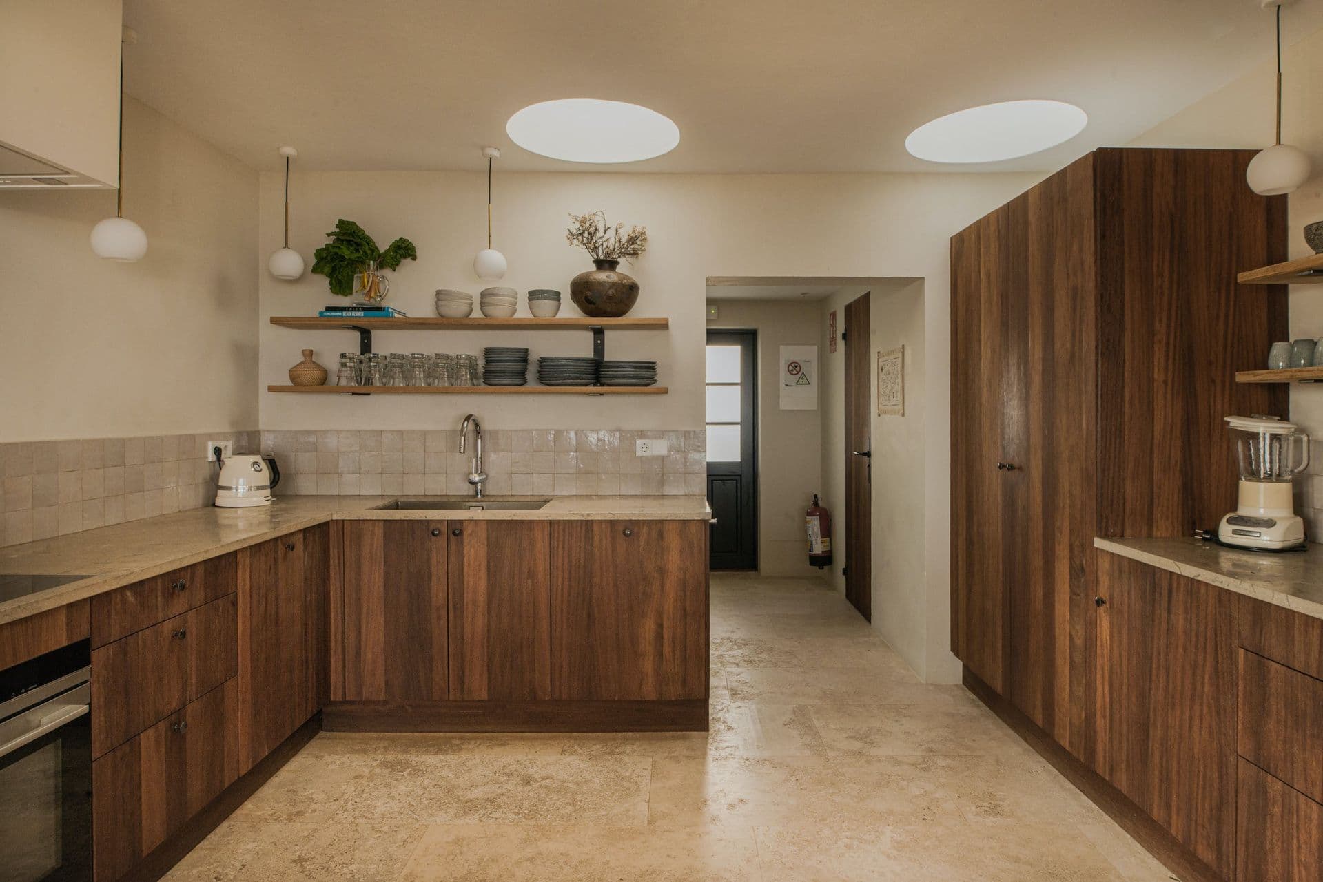 Walnut kitchen cabinetry with open shelving and skylights above at New Beat