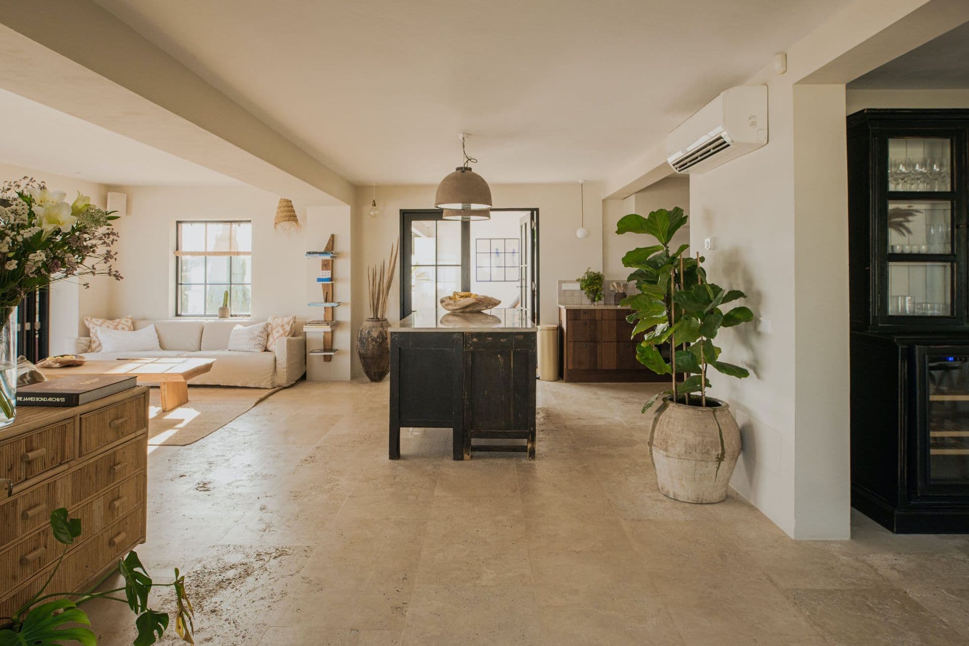 Open plan living space with dark cabinetry and travertine flooring at New Beat