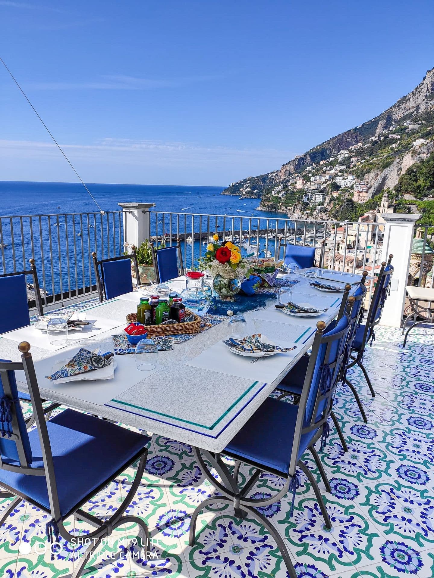 Long outdoor dining table on the majolica-tiled terrace set for a group