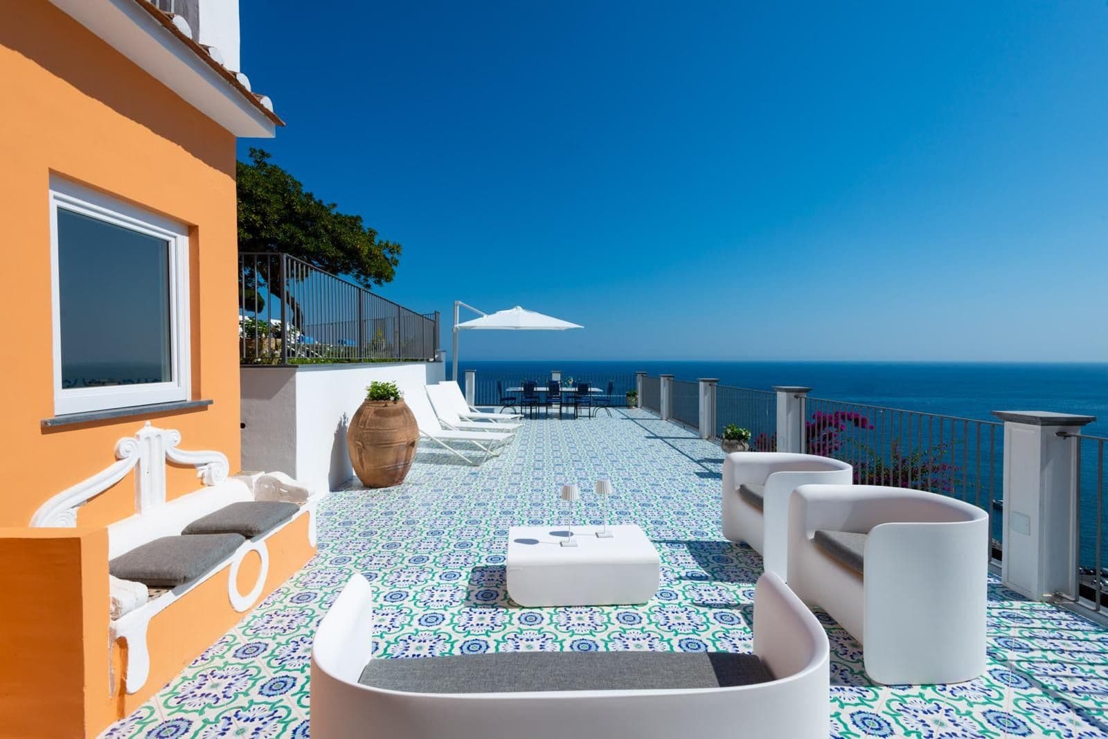Hand-painted tiled terrace with curved lounge seating and sea views