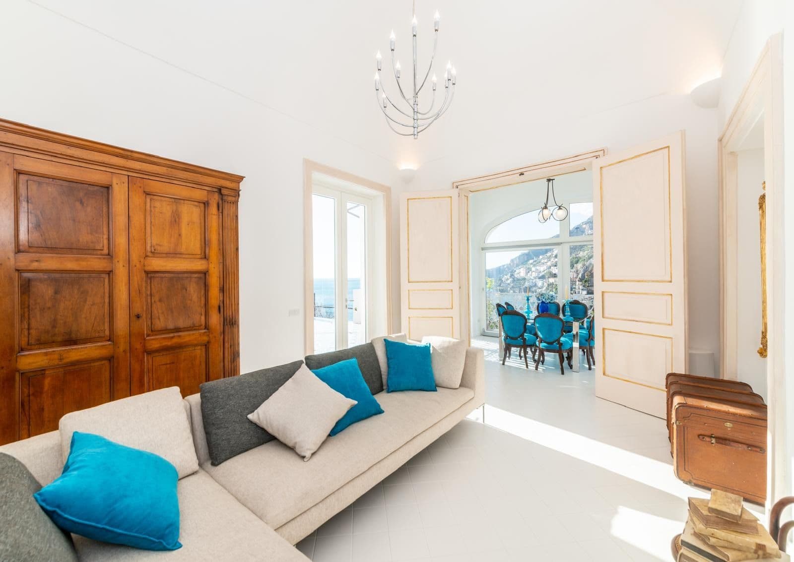 Living room with cream sofas, turquoise cushions and an antique armoire
