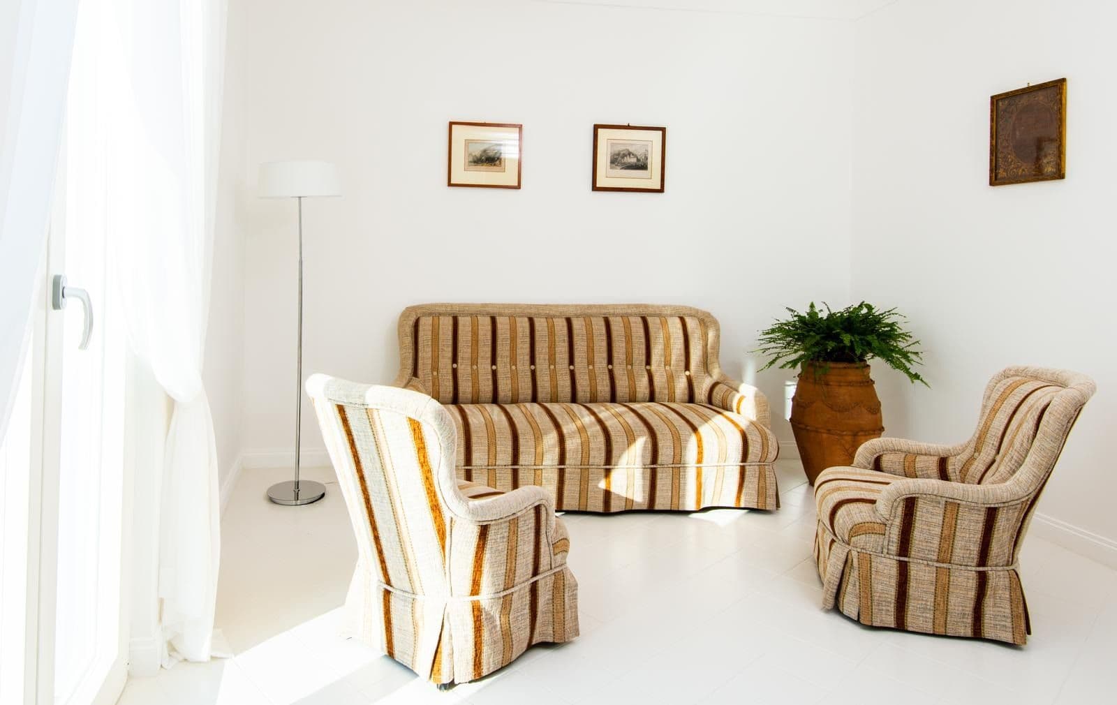 Bright sitting room with striped armchairs and a potted plant