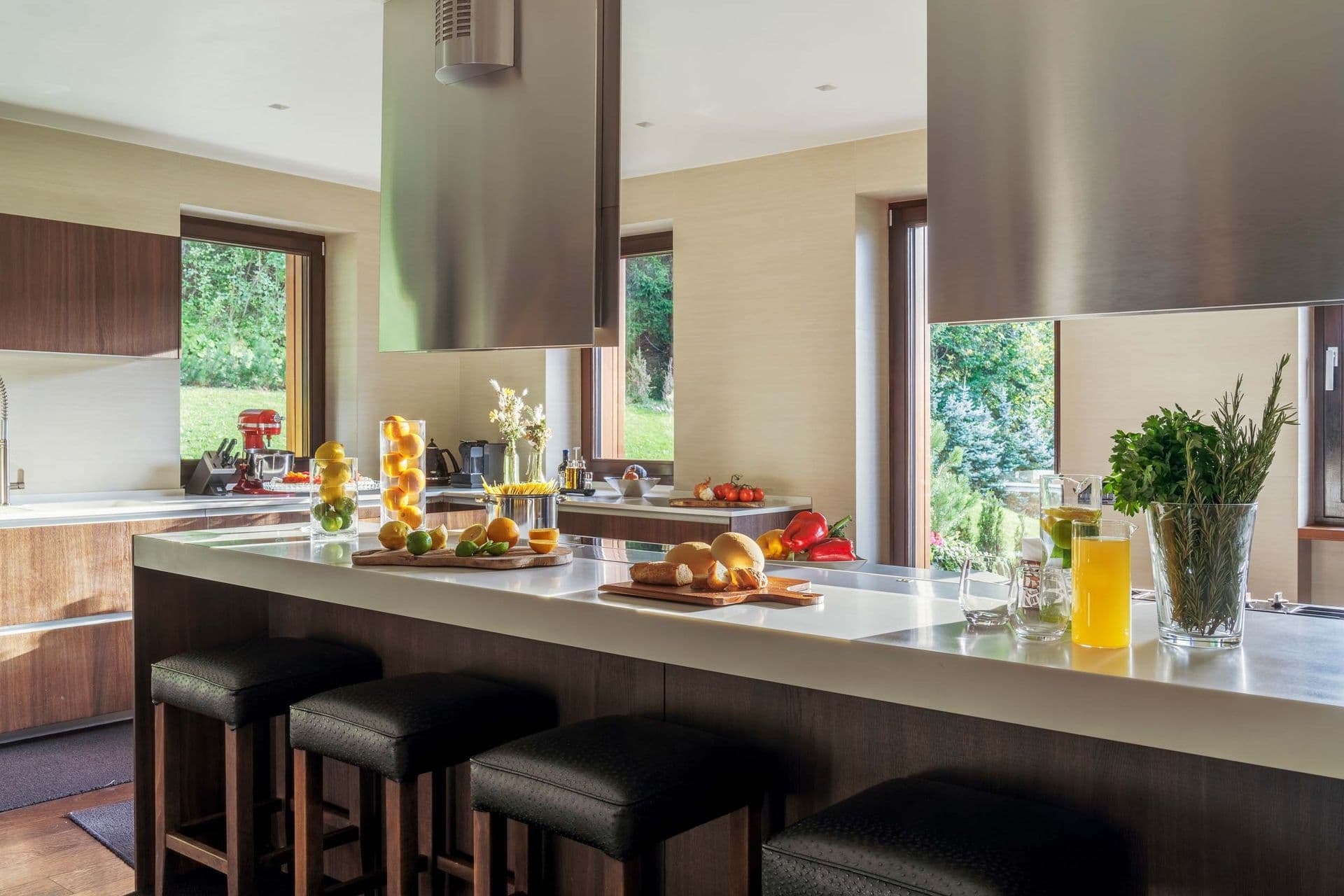 Kitchen island with leather bar stools beside mountain-view windows at Dolomite Prestige, Cortina d'Ampezzo