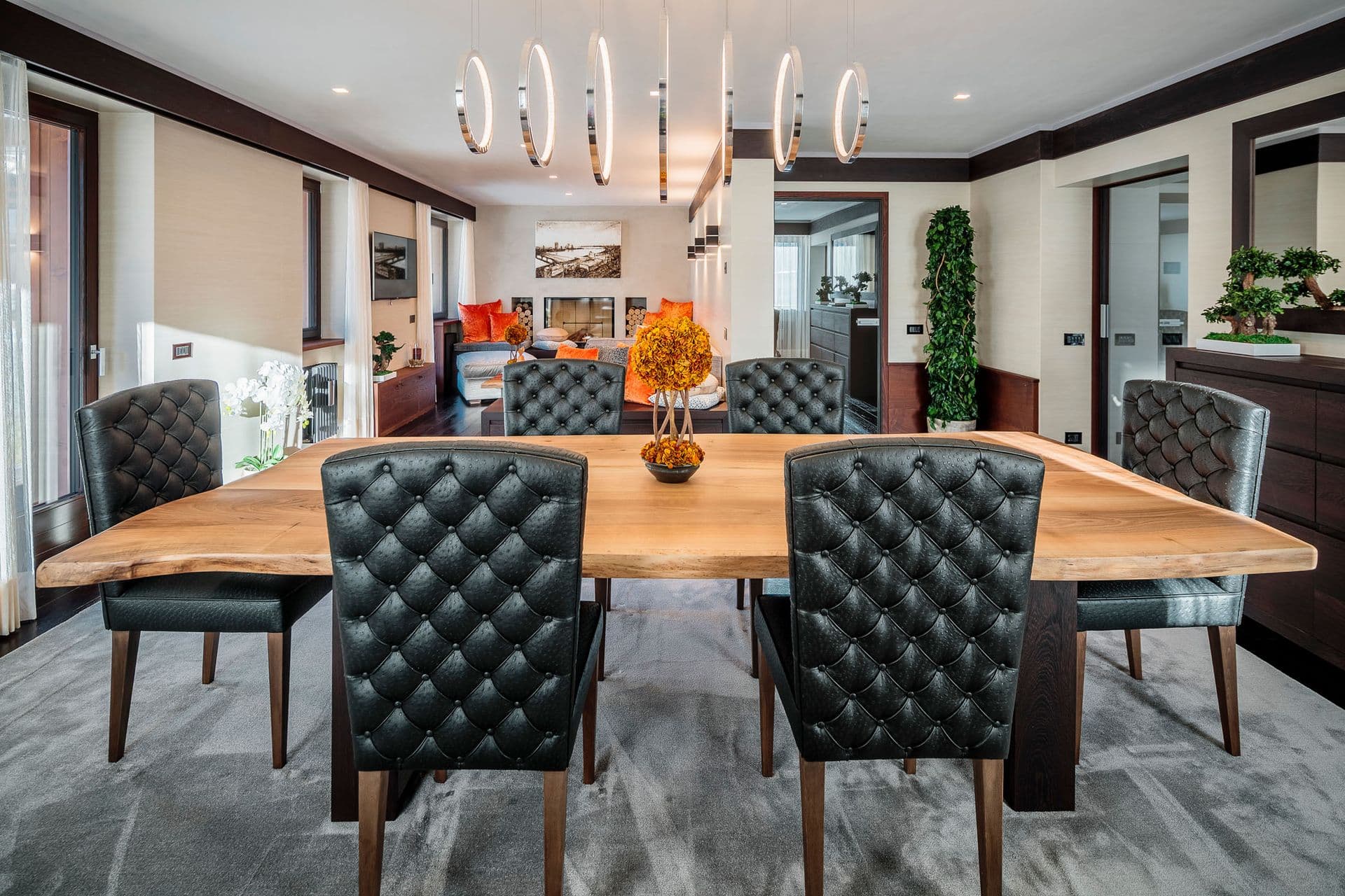 Dining room with a live-edge table and tufted leather chairs under pendant lights at Dolomite Prestige, Cortina d'Ampezzo