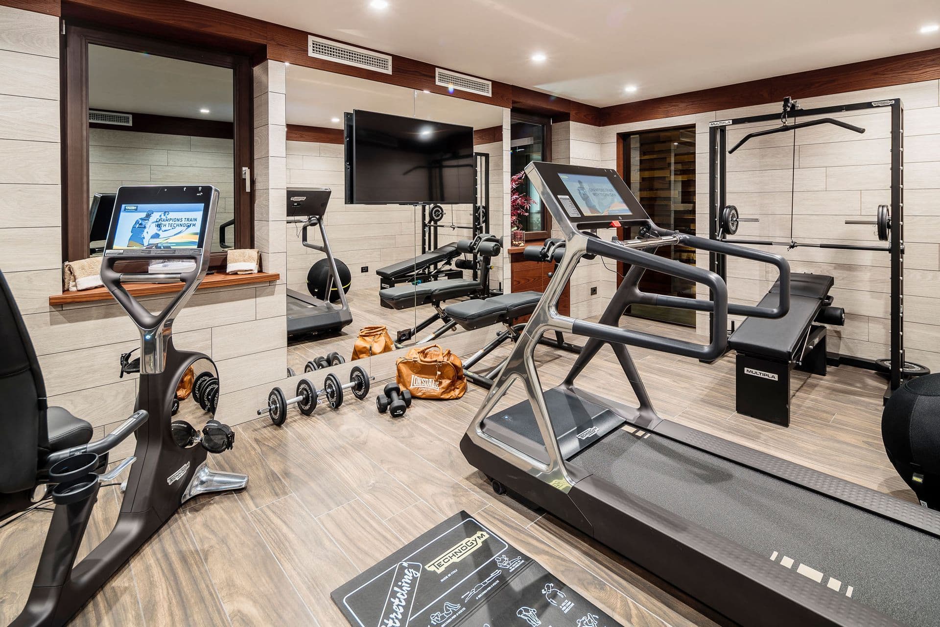 Home gym with cardio and weights equipment and a television at Dolomite Prestige, Cortina d'Ampezzo