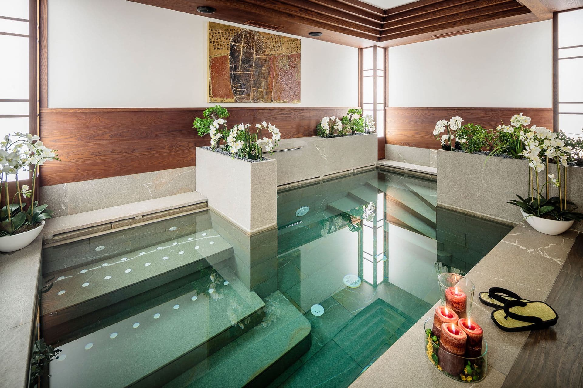 Indoor swimming pool lit green with orchids and stone walls at Dolomite Prestige, Cortina d'Ampezzo
