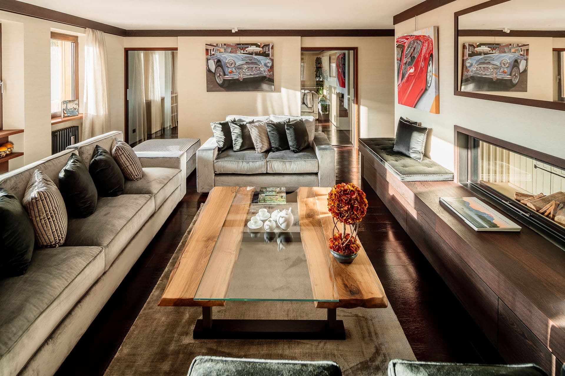 Living and dining lounge with a grey sofa and timber table by the fireplace at Dolomite Prestige, Cortina d'Ampezzo