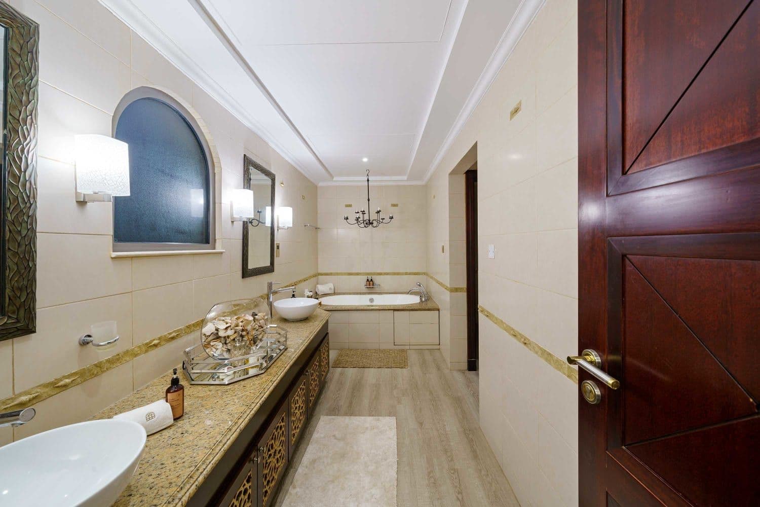 Bathroom with a built-in bathtub below an arched window at A Place in the Palms, Palm Jumeirah