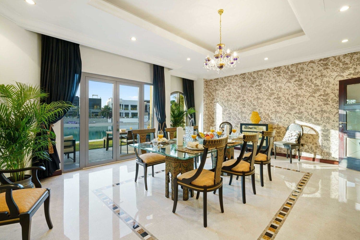 Glass dining table set for eight beside lagoon-facing windows at A Place in the Palms, Palm Jumeirah