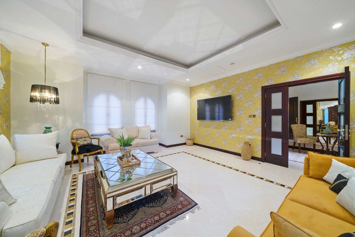 Family television room with pale sofas and patterned wallpaper at A Place in the Palms, Palm Jumeirah
