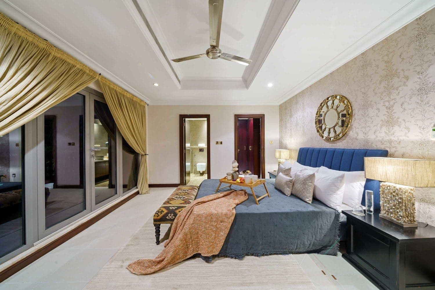 Master bedroom with a navy bed, gold curtains and terrace doors at A Place in the Palms, Palm Jumeirah