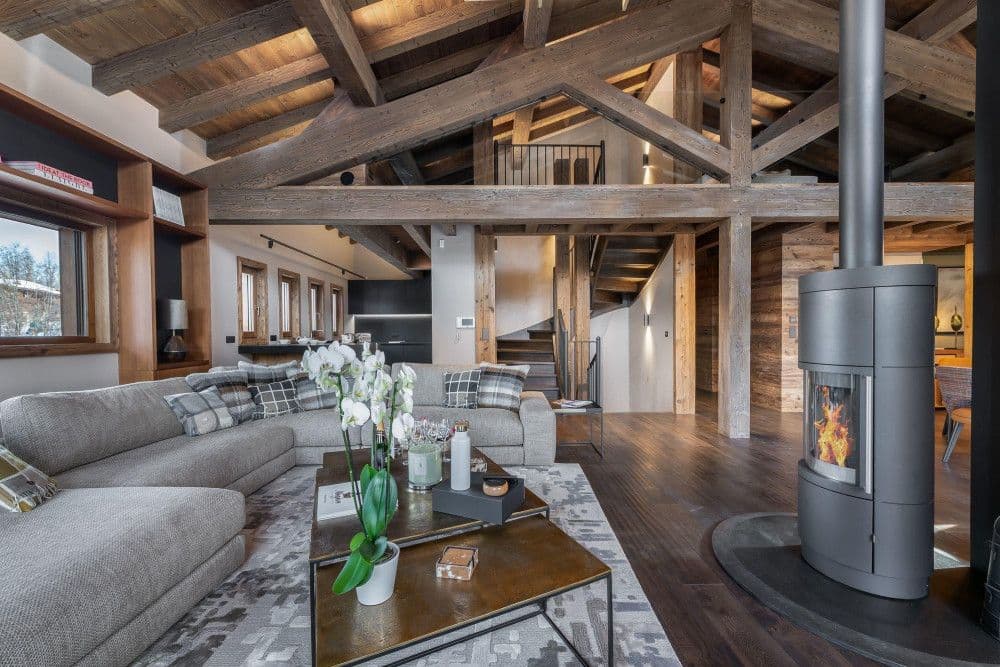 Living room with a sculptural wood-burning stove under vaulted beams at Mont d'Arbois 6, Megeve