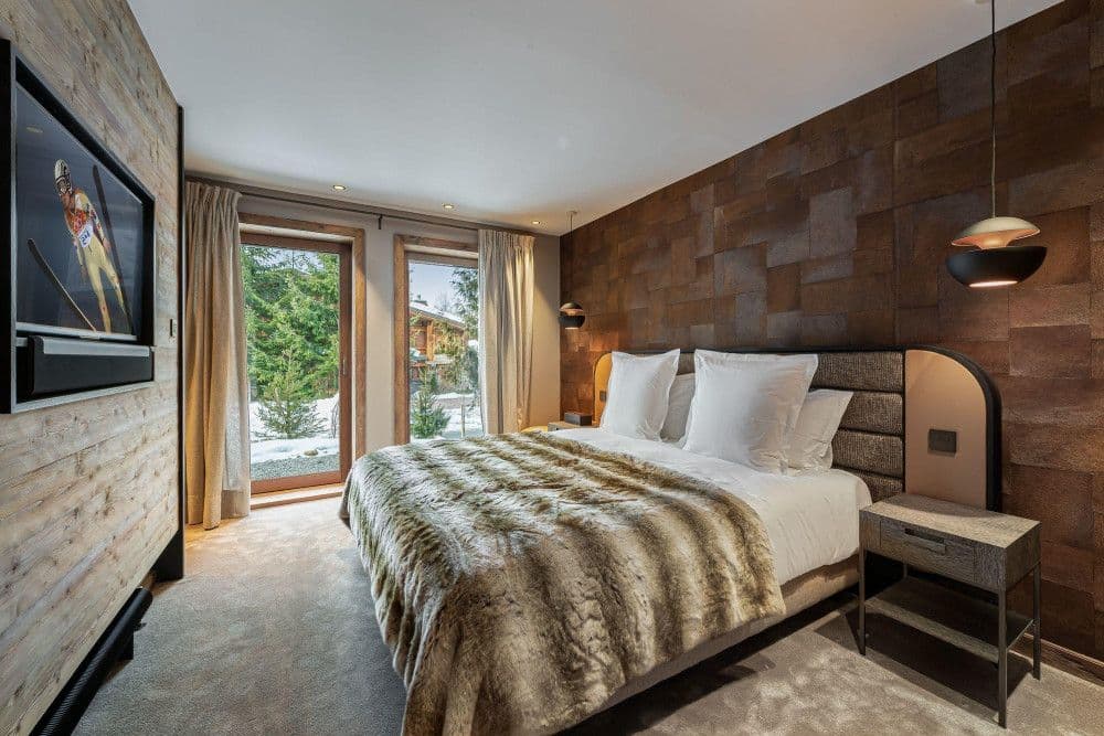 Master bedroom with a timber feature wall and fur throw at Mont d'Arbois 6