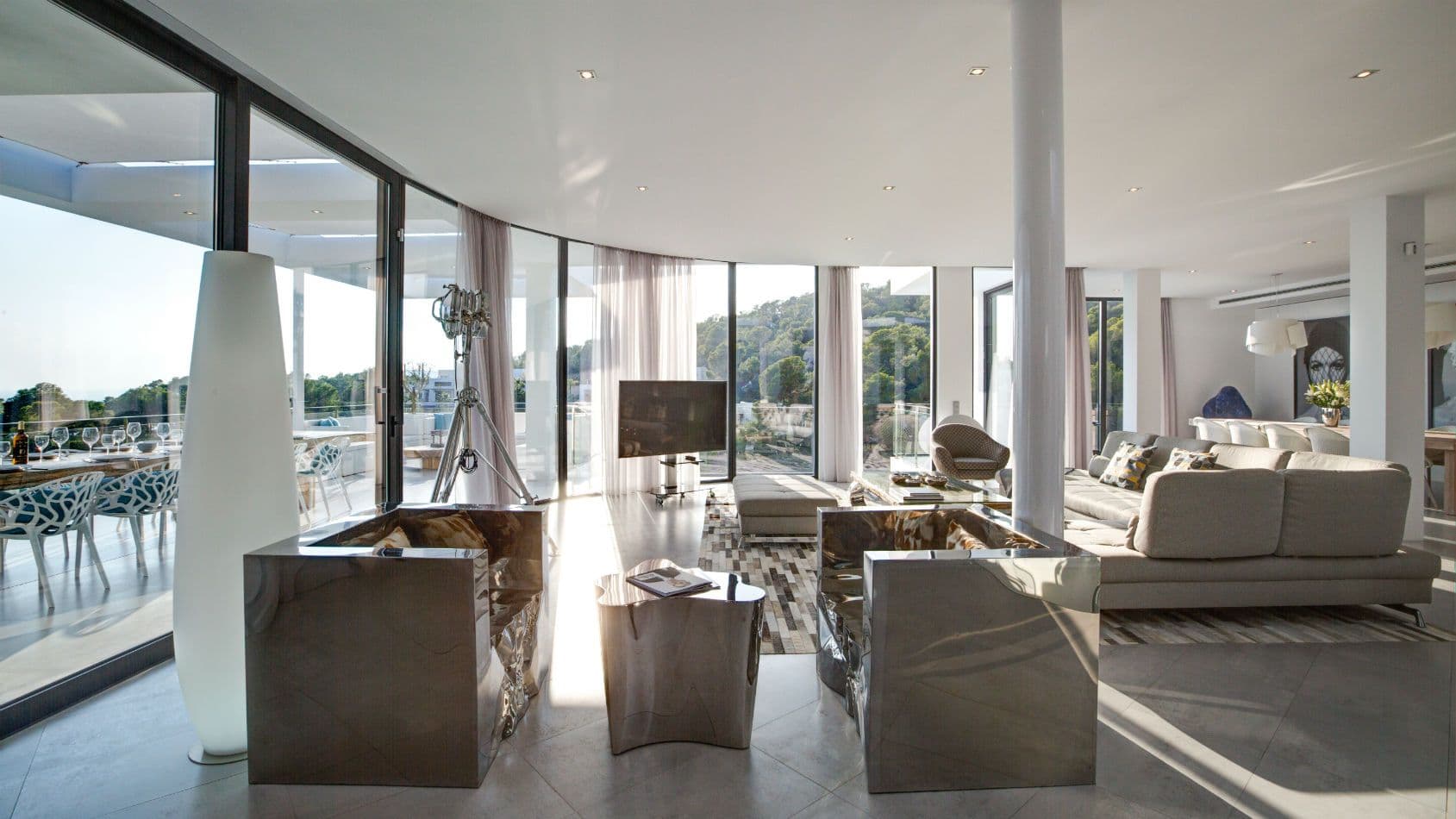 Lounge with glass walls opening to the forest and chrome tables at Baby, You Can Drive My Car, Ibiza