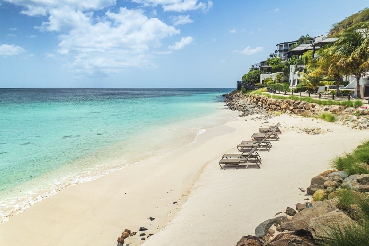 White-sand beach and turquoise water below the resort at Hills of Antigua