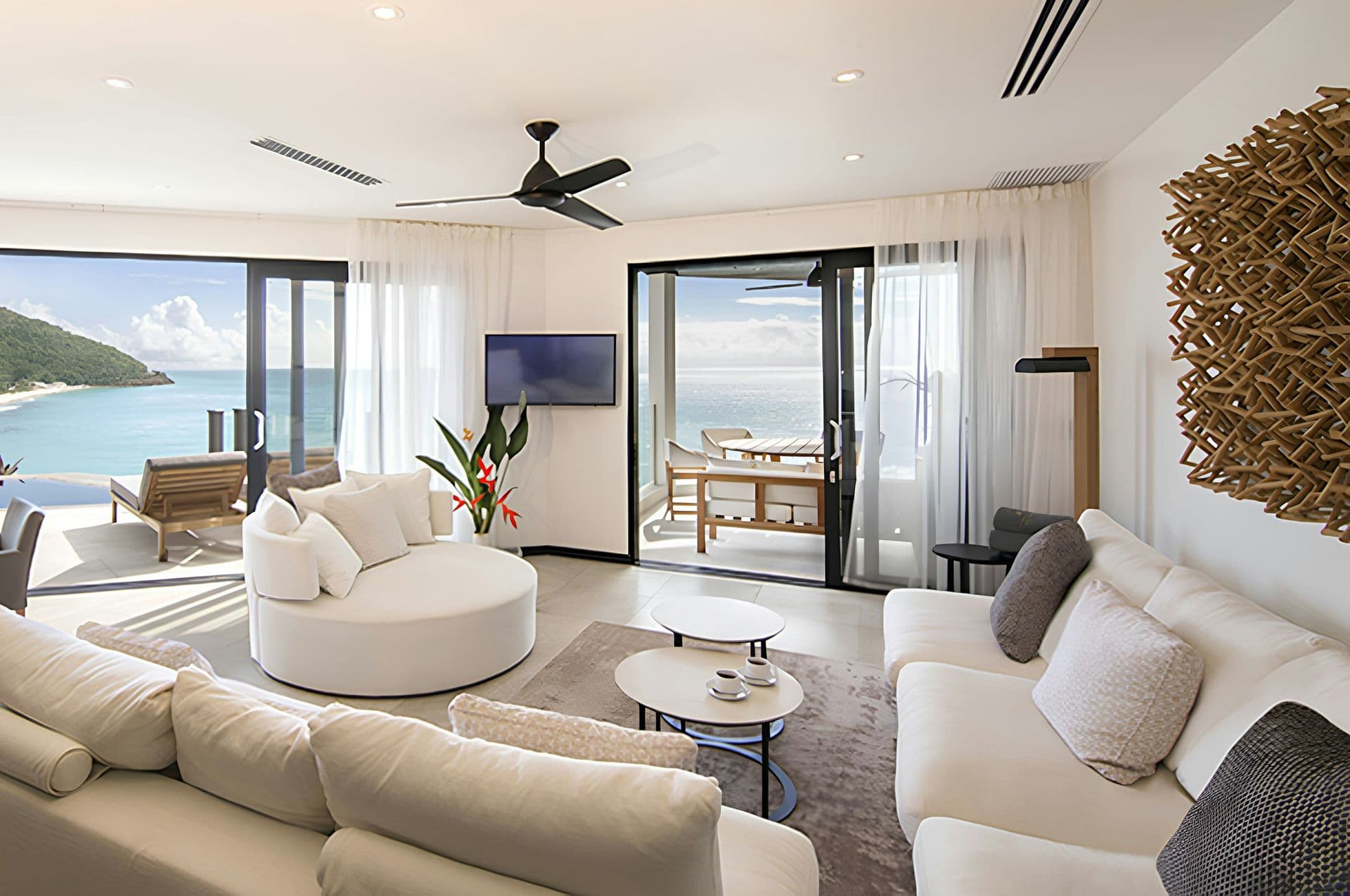 Open-plan living room with a round sofa opening to the sea at Hills of Antigua