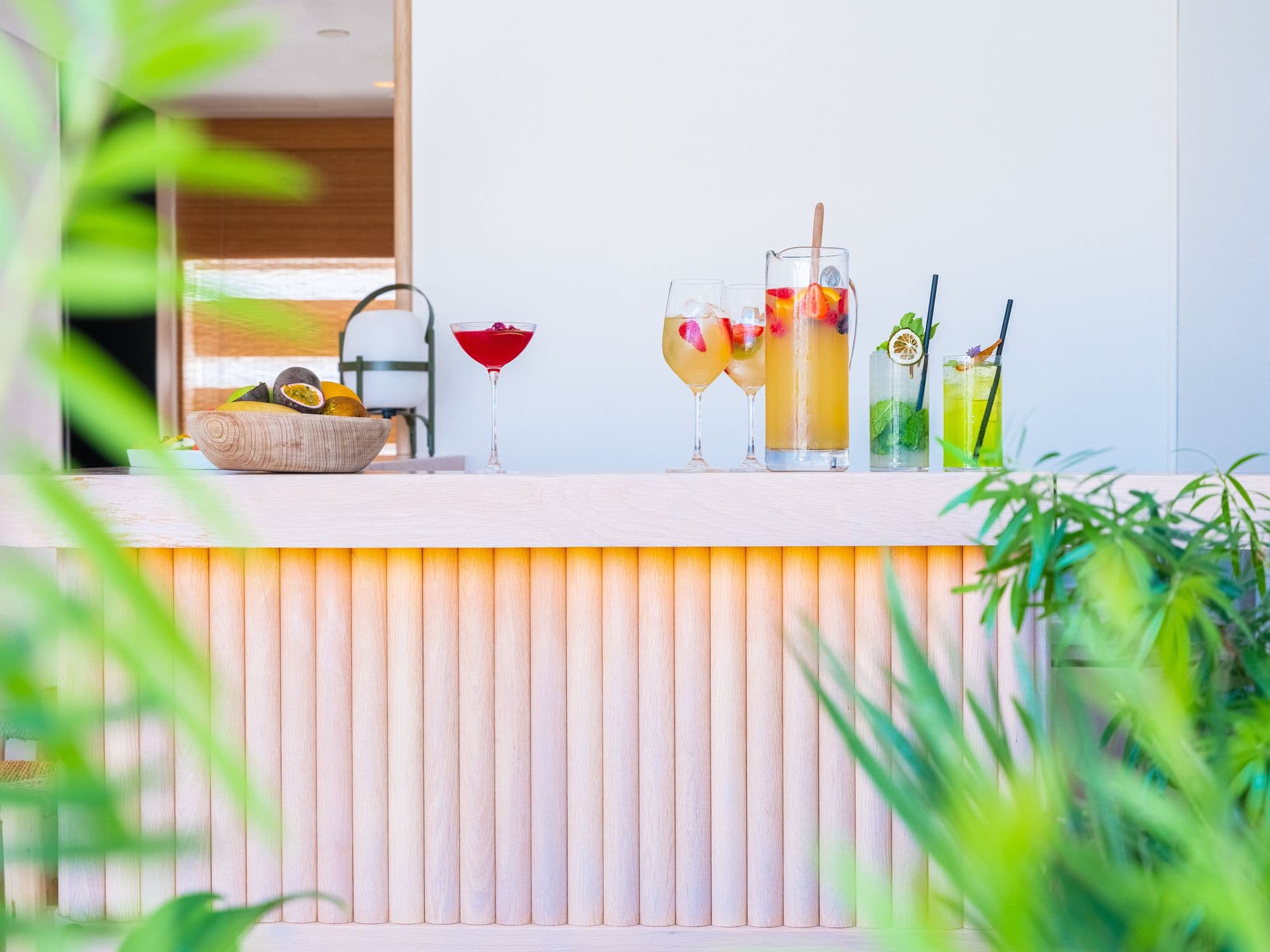 Fluted pink outdoor bar counter set with fresh cocktails among palm fronds
