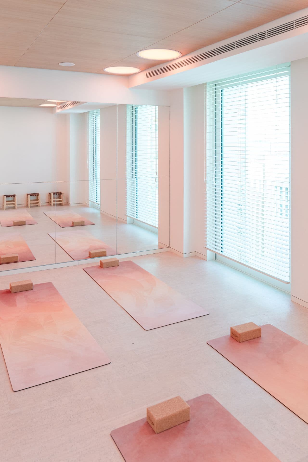 Sunlit yoga and pilates studio with pink mats and blocks laid out in rows