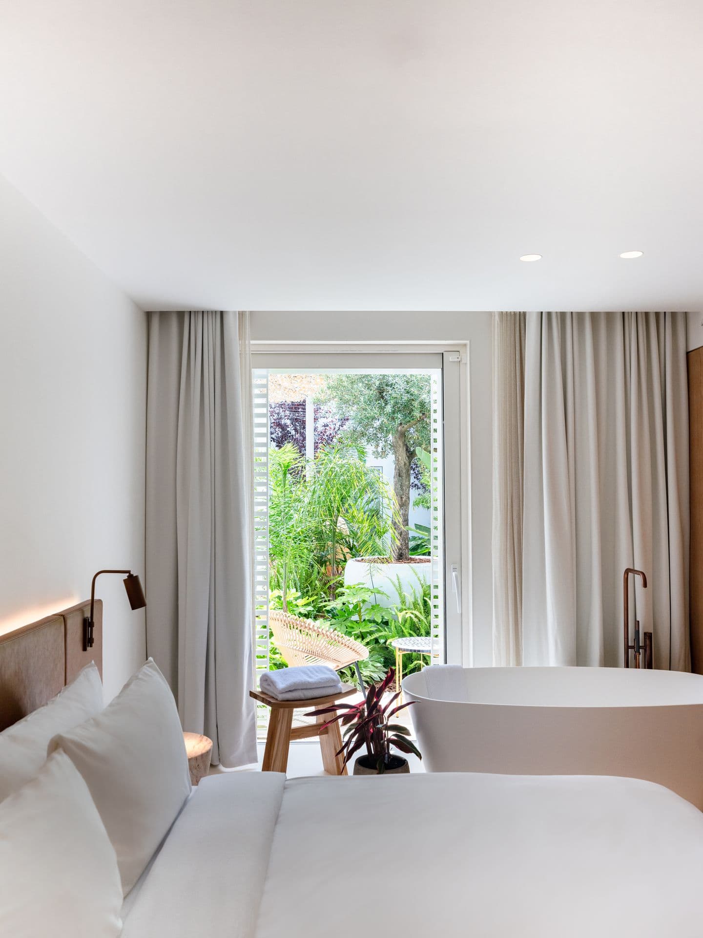 Bedroom opening onto a freestanding bathtub and private garden view
