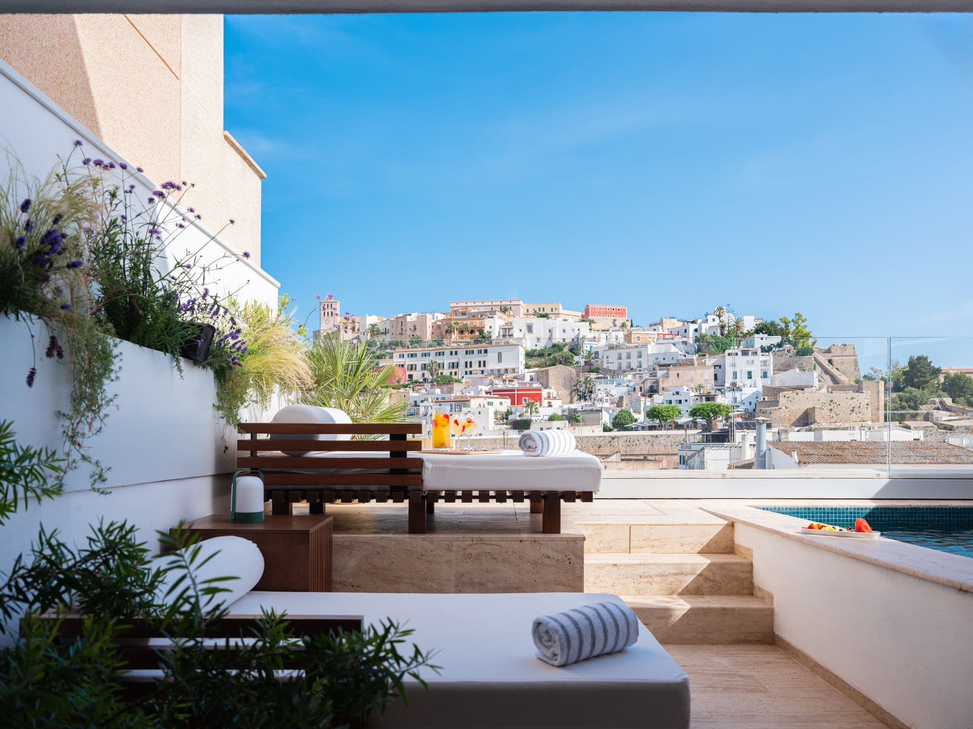 Rooftop terrace daybed and low table looking out over a whitewashed hillside town