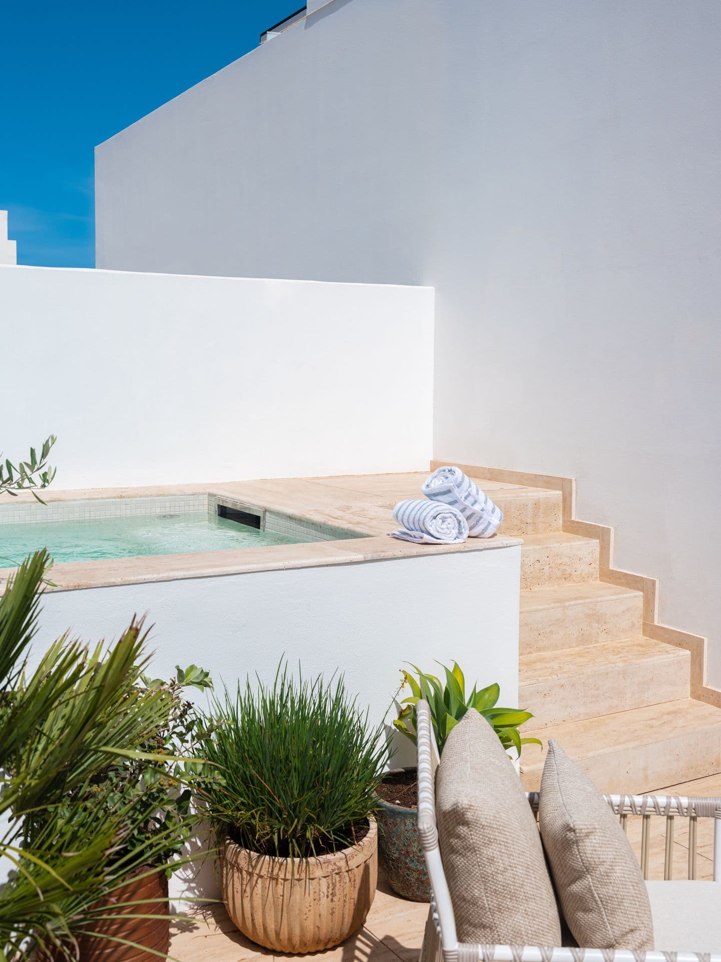 Rooftop plunge pool steps beside a sunlit whitewashed wall