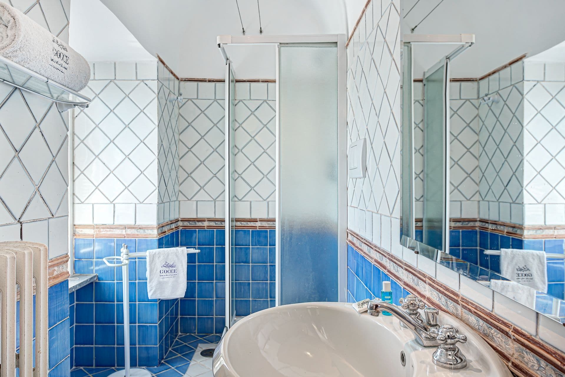 Bathroom with blue diamond-pattern tiling and a walk-in shower.