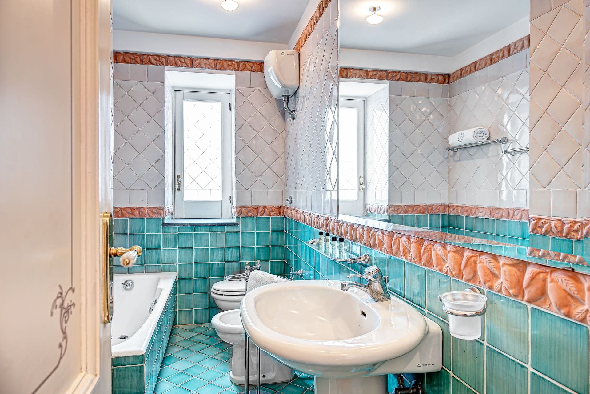 Vintage bathroom with teal and terracotta tiling.