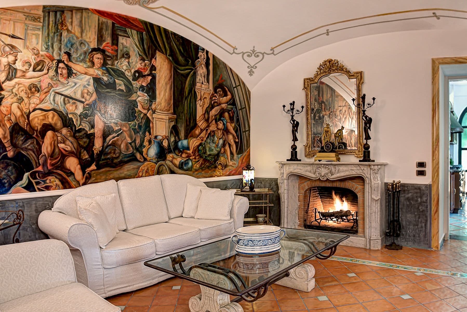 Grand salon with a painted tapestry ceiling and open fireplace.