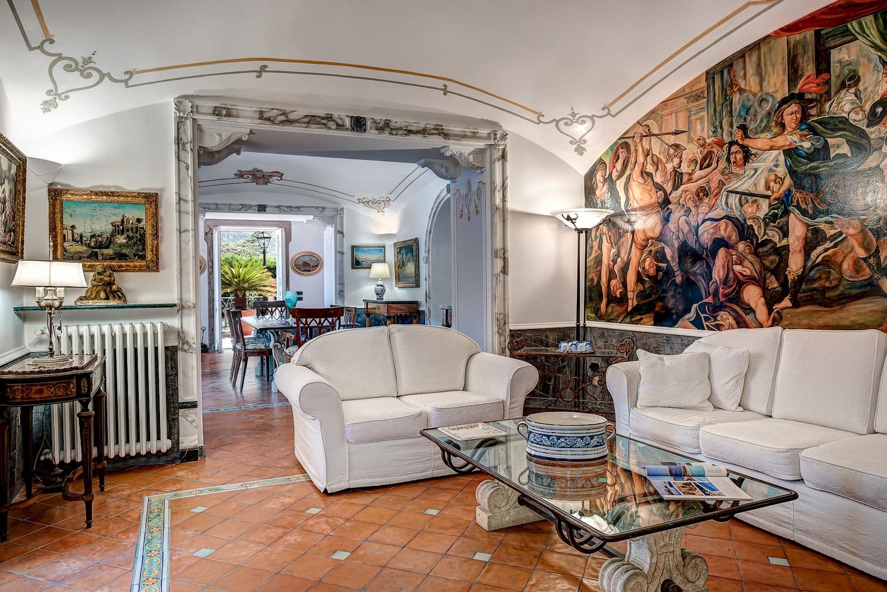 Frescoed hall with white sofas and a marble fountain feature.