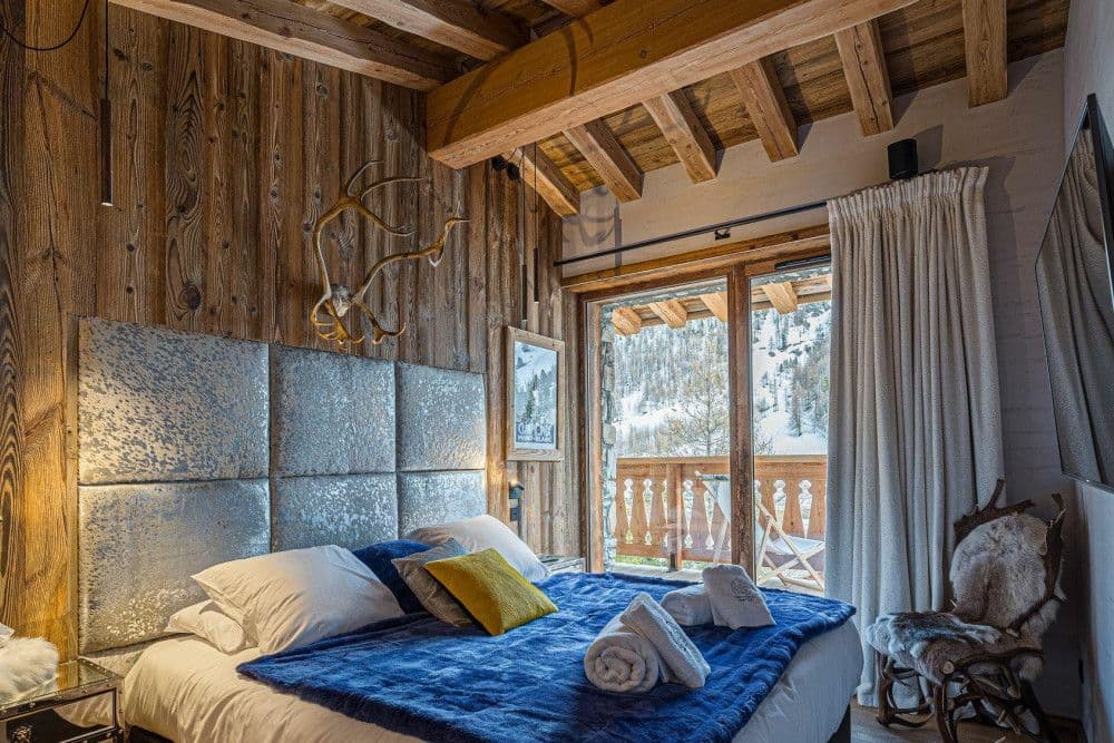 Double bedroom with a quilted headboard and mountain window at Le Fornet 2