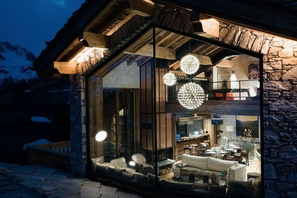 Stone chalet with a lit glass gable at twilight above Val d'Isere at Le Fornet 2