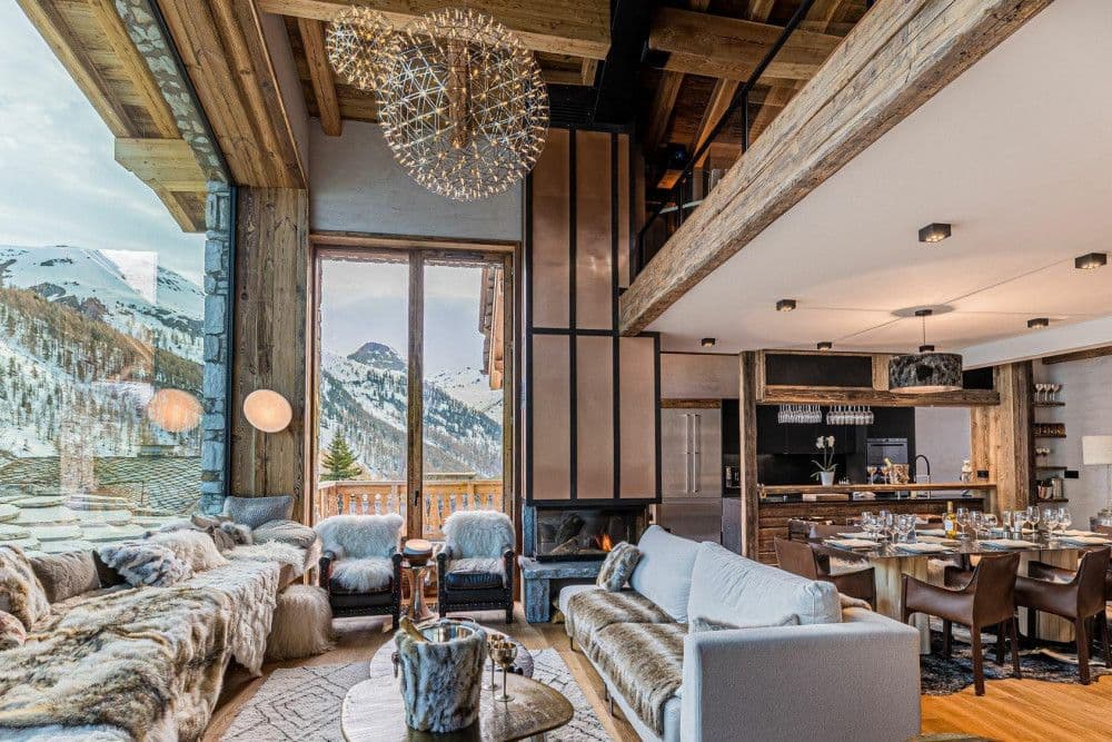 Open-plan living and dining room with a fire and mountain view at Le Fornet 2