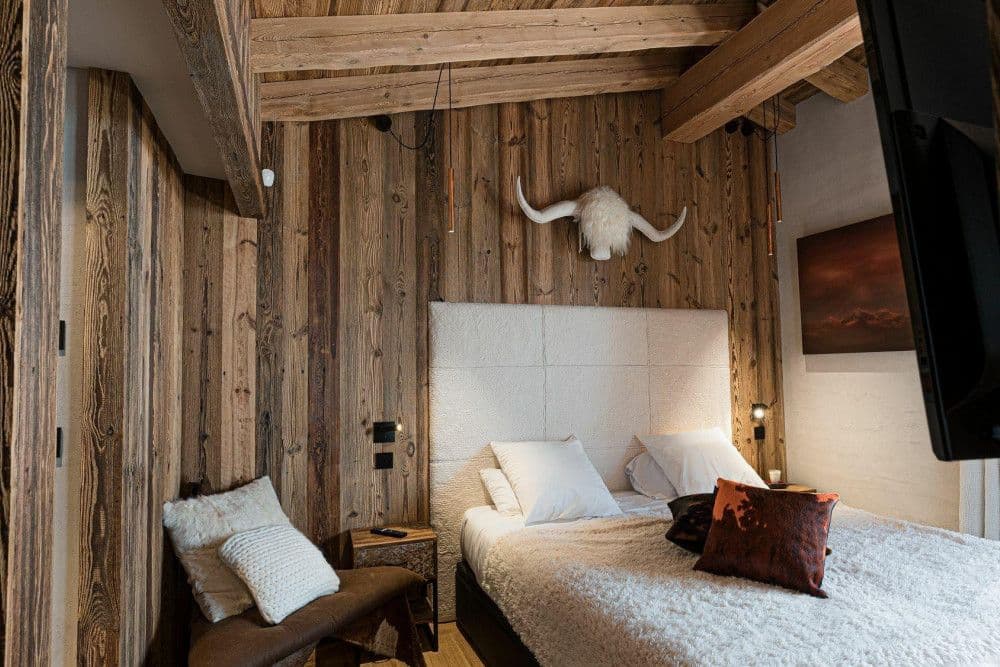 Guest bedroom with a white headboard and alpine art at Le Fornet 2