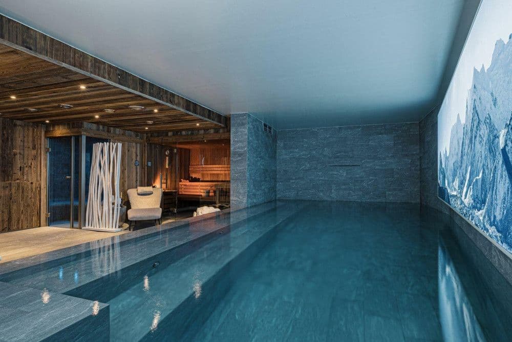Long indoor swimming pool with an alpine mural at Le Fornet 2