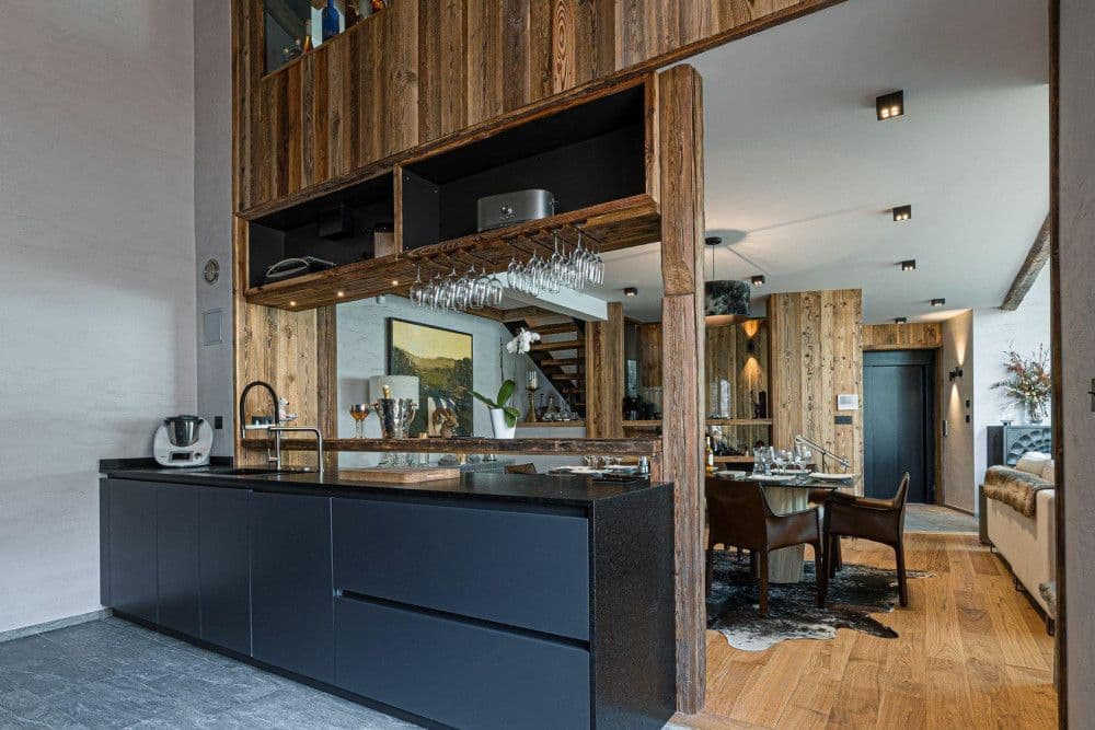 Contemporary kitchen with a dark island beneath old timber beams at Le Fornet 2