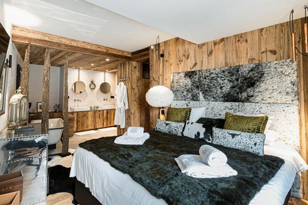 Master bedroom with a cowhide headboard and en-suite bath at Le Fornet 2