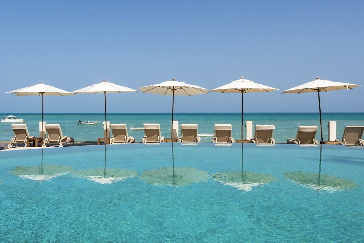 Shared resort infinity pool lined with parasols above the sea at Caribbean Wonder
