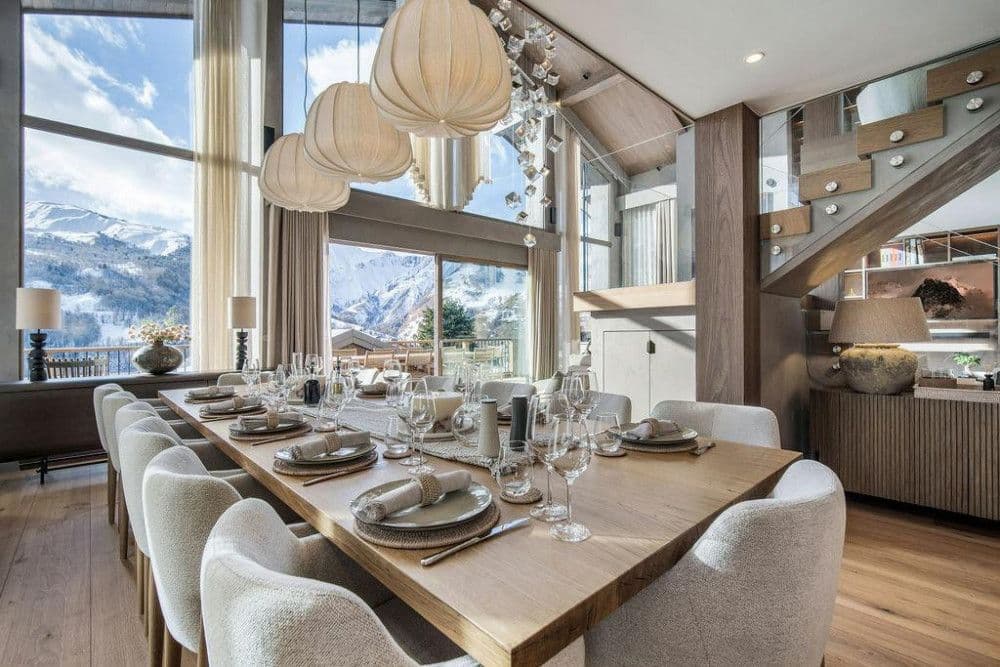 Dining room beneath double-height windows with mountain views at Saint Martin de Belleville 12
