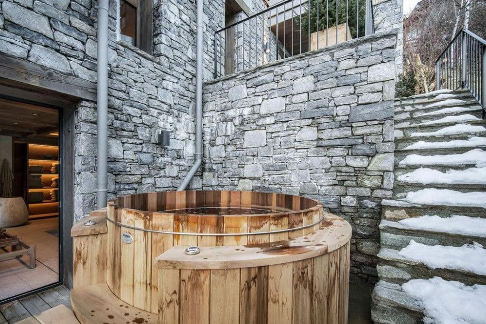 Outdoor barrel hot tub in a snowy stone courtyard at Saint Martin de Belleville 12