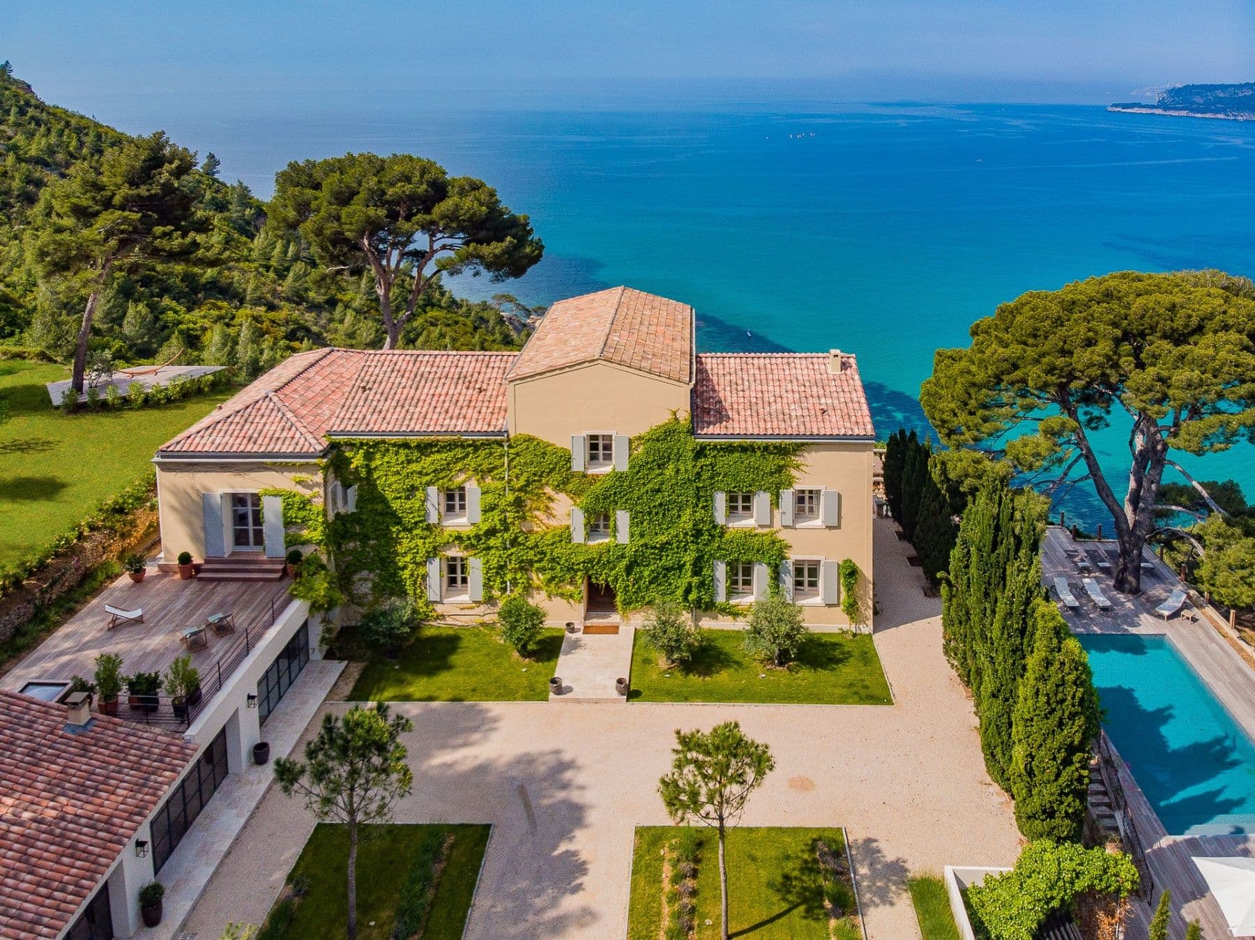 Aerial view of the ivy-clad villa, garden and pool above the sea at Be Our Guest, Cassis, France
