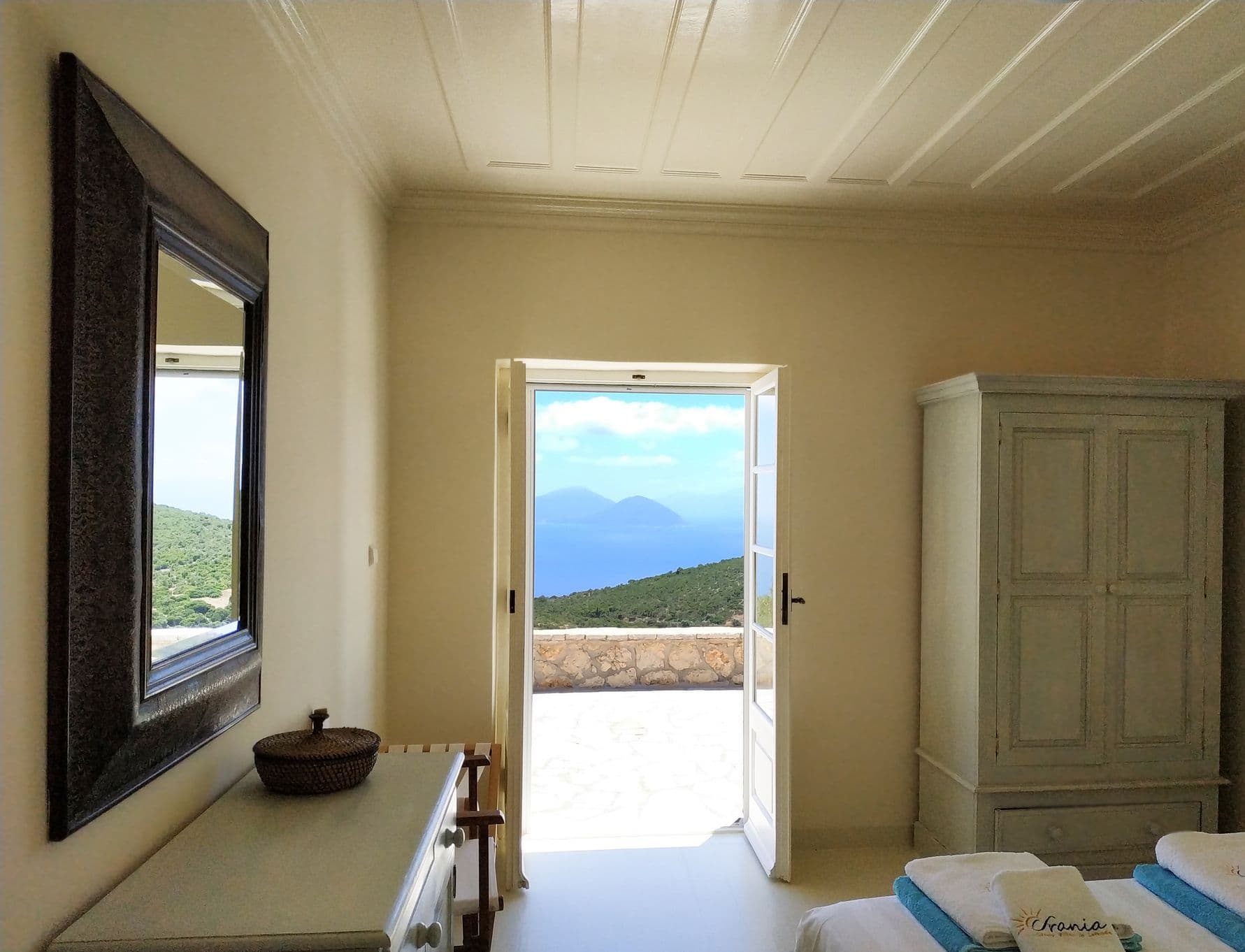 Bedroom with open double doors framing a distant sea view