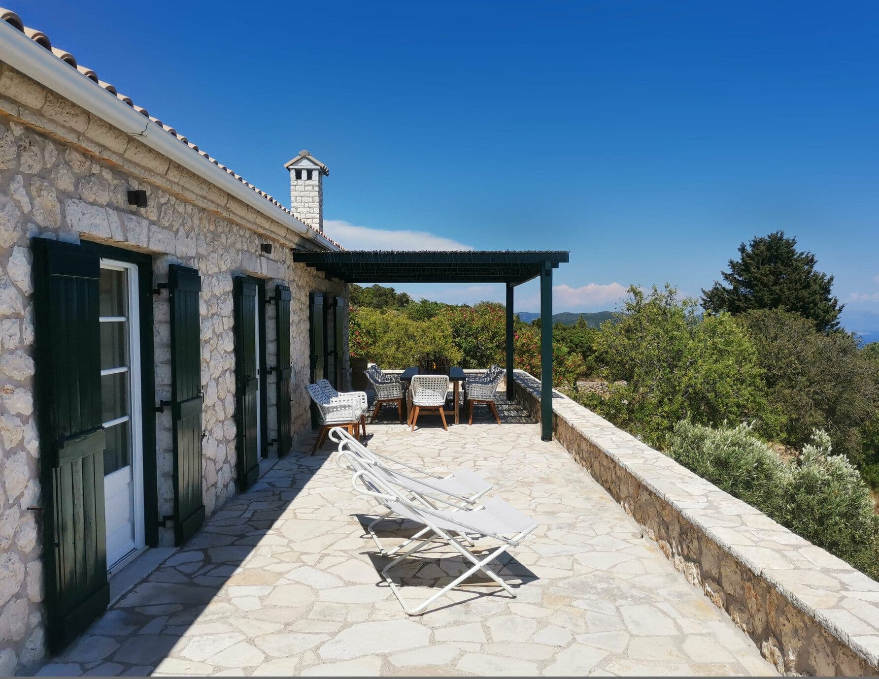 Stone villa terrace with wooden pergola, loungers and olive grove views