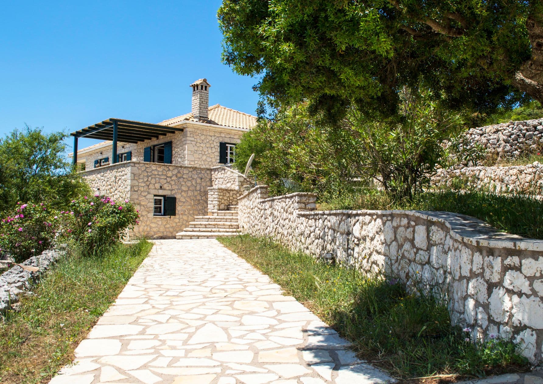 Paved stone pathway leading up to the traditional stone villa entrance