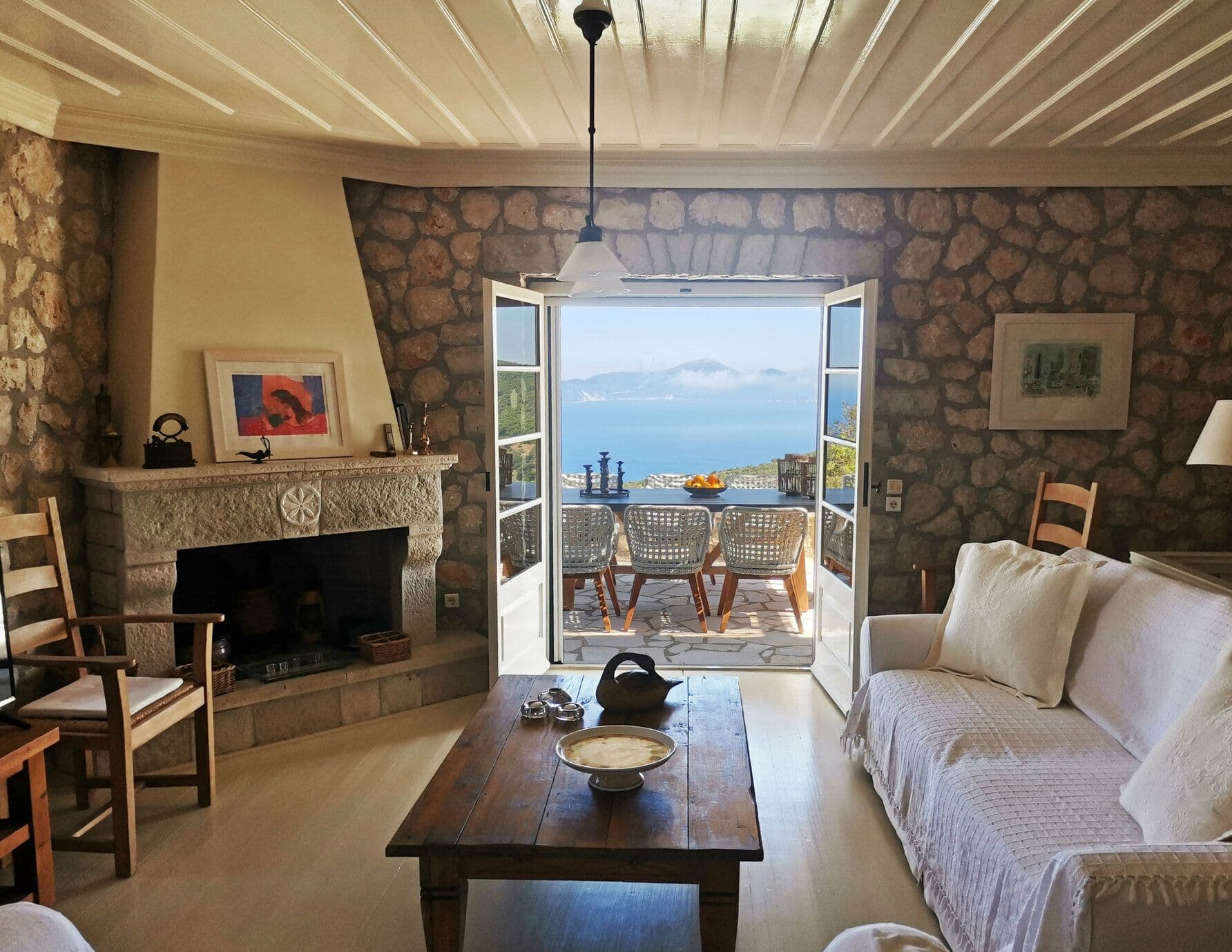 Living room with a stone fireplace and French doors opening onto sea views
