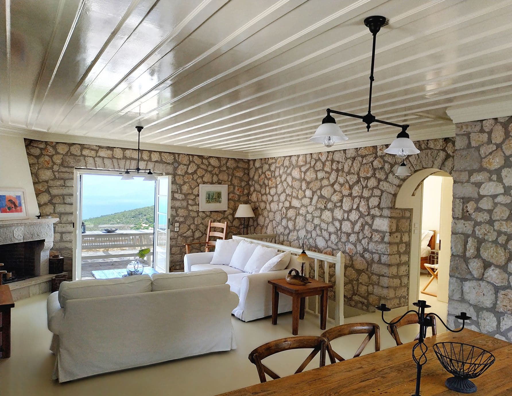 Living room with exposed stone walls and white slip-covered sofas