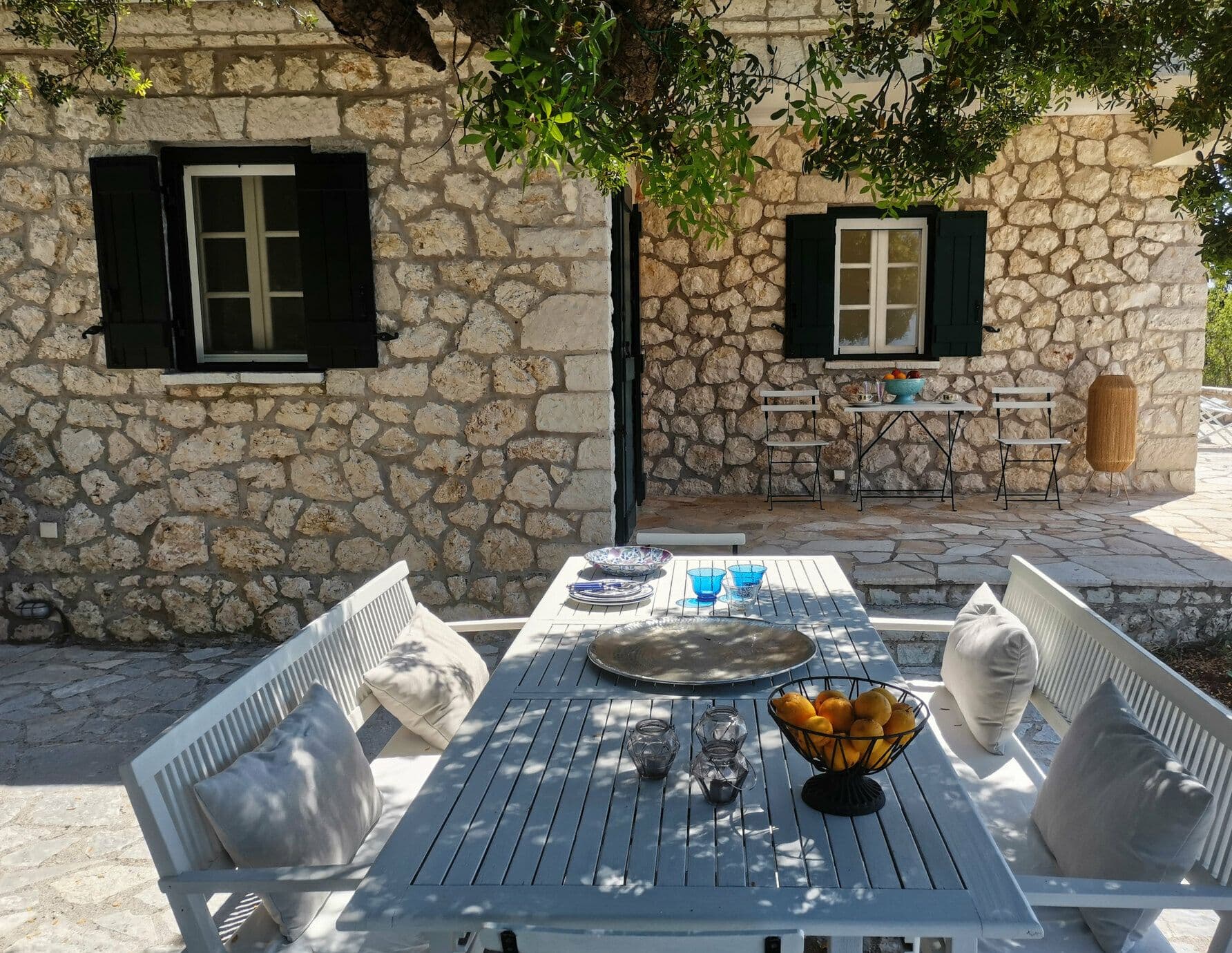 White wicker outdoor dining set on a shaded stone terrace