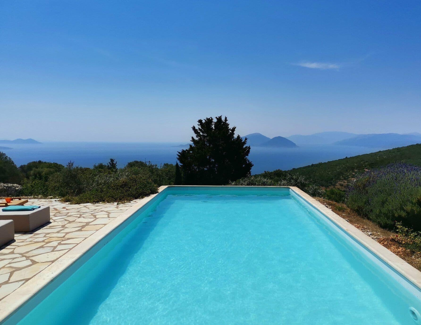 Infinity pool overlooking the Ionian Sea and distant mountains under a clear sky